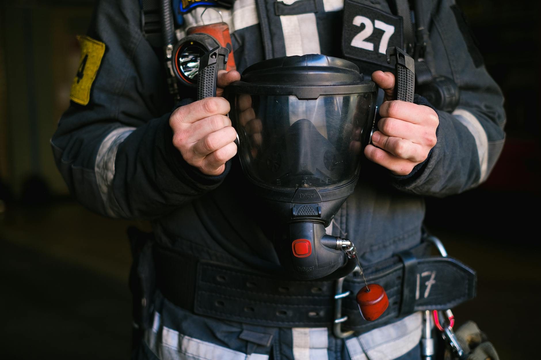 Firefighter holding SCBA mask with turnout gear visible