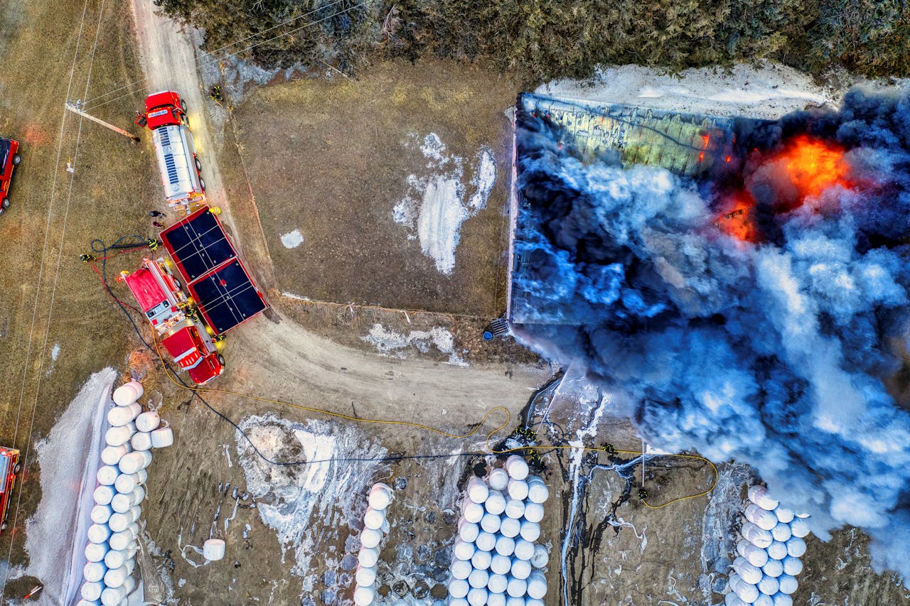 Aerial drone view of firefighters battling structure fire with visible flames and smoke