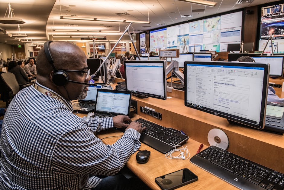 Emergency operations center operator at multi-monitor CAD workstation with large display screens