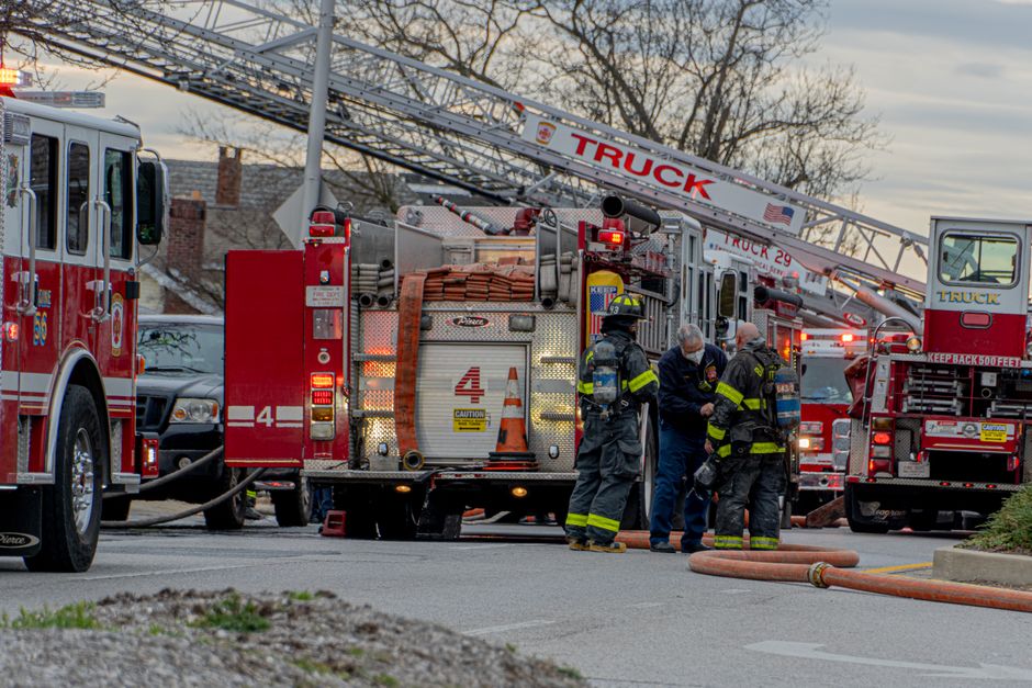 Firefighters coordinating at urban emergency scene with multiple fire trucks