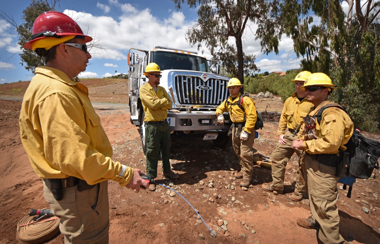 American wildland firefighter crew in yellow Nomex during post-incident debrief