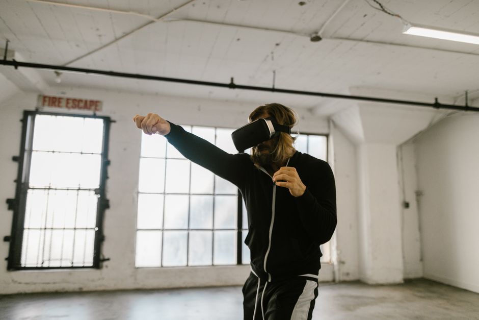 Person wearing a VR headset with arms raised, demonstrating virtual reality interaction and immersive technology