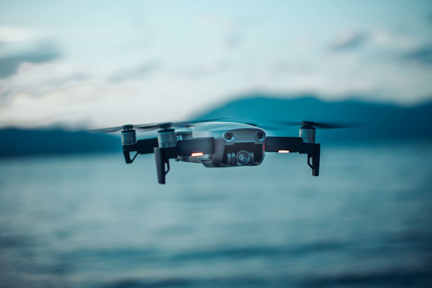Quadcopter drone hovering above a wildfire perimeter at dusk