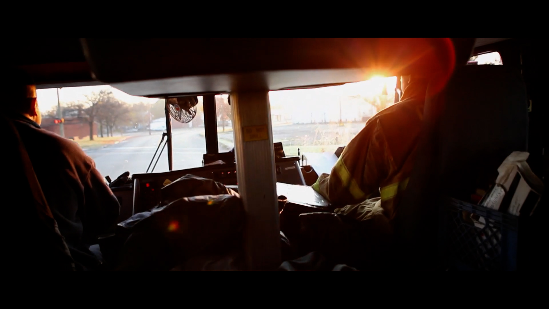 Firefighter in full turnout gear on the fireground at sunrise beside a fire engine