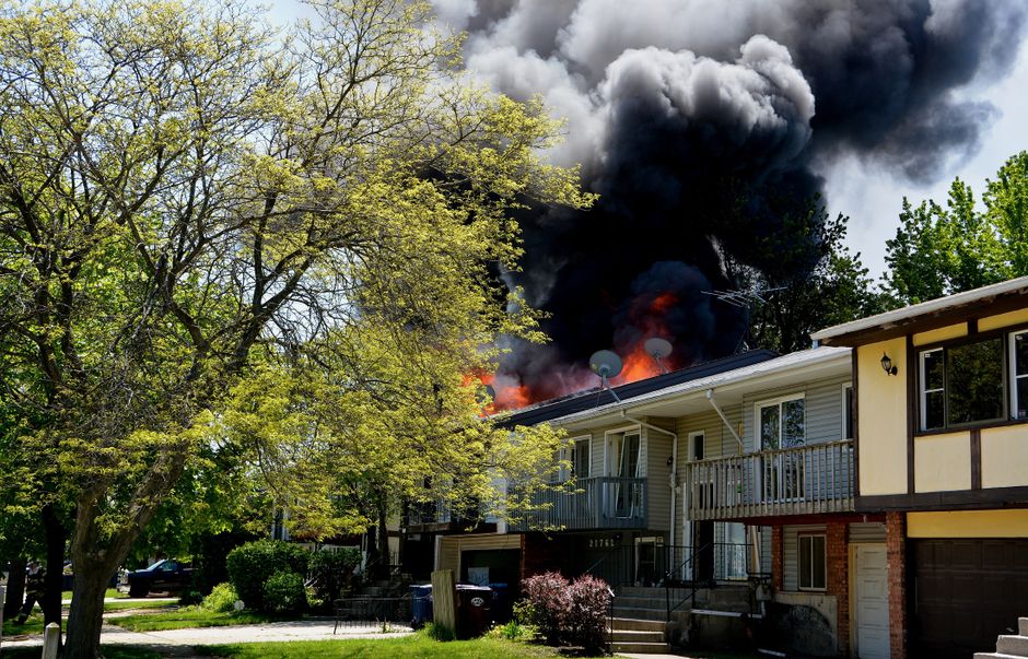 Suburban house fire with smoke rising from the roof, representing AI fire-behavior prediction research