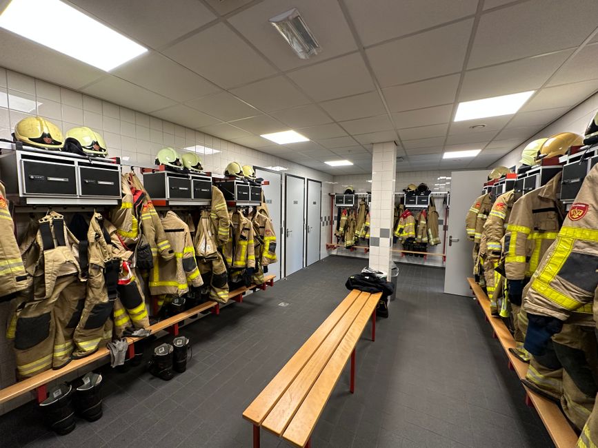Locker room with firefighter uniforms and equipment hanging in a fire station