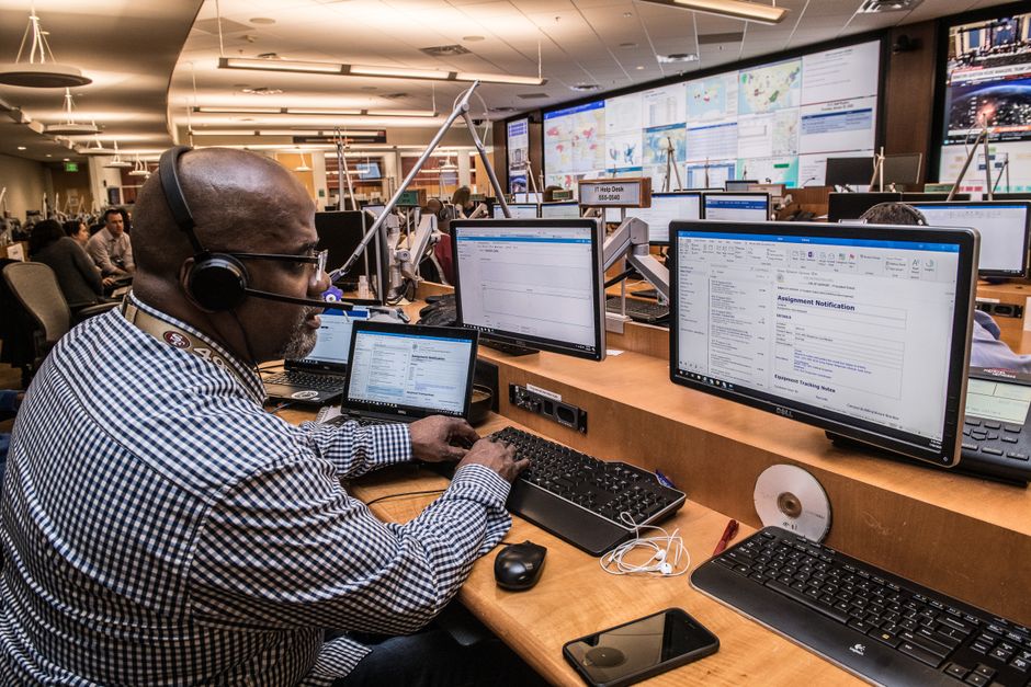 Emergency dispatch operator working at a multi-screen call center console
