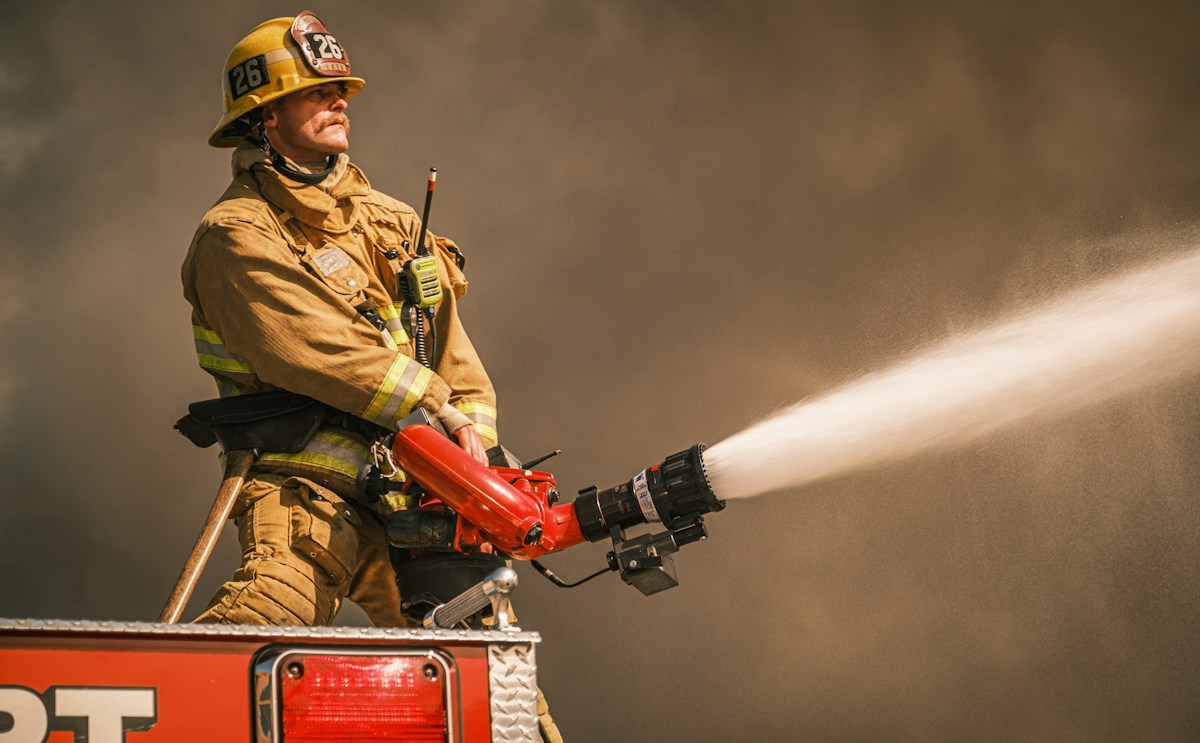 LAFD firefighter operating a deck gun during an active structure fire with heavy smoke