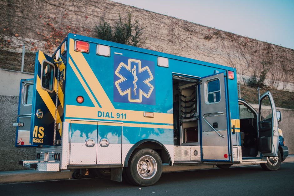 EMS paramedics in uniform beside an ambulance with Dial 911 visible on vehicle