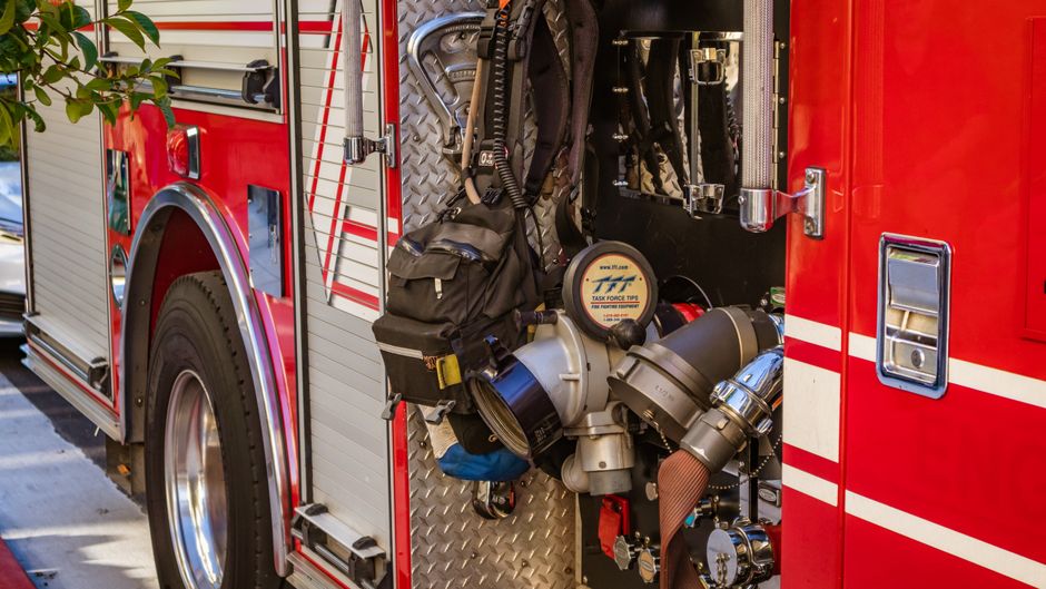 Red fire engine compartment with hoses and breathing apparatus at a station